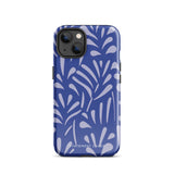 An iPhone encased in the "Mariposa Azul" by Statement Cases, featuring a blue design with an abstract white leaf pattern. The case combines curved and pointed shapes and provides dual-layer protection with TPU lining and impact-resistant polycarbonate. Camera lenses and other top elements remain unobstructed, and "Statement Cases" is inscribed at the bottom.