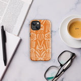 A Savannah Ardiente for iPhone from Statement Cases, featuring a dual-layered phone case in orange with a floral pattern showcasing cream-colored flowers, leaves, and geometric shapes. This impact-resistant polycarbonate case displays "STATEMENT CASES" at the bottom and reveals the camera lenses at the top left corner.