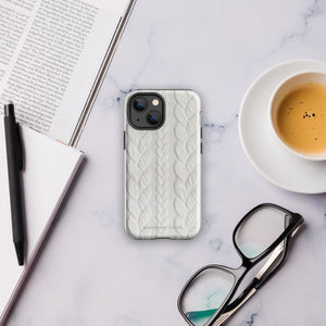 The Cozy Knit Bliss for iPhone by Statement Cases is designed for a smartphone with three rear cameras. It offers dual-layer protection and features a textured white pattern that looks like knitted fabric. The bottom of the case has the text "STATEMENT CASES" engraved, ensuring both style and impact-resistant durability.