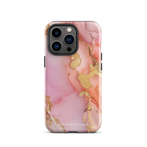 The Gold Blush Marble for iPhone showcases a glossy, marble-patterned case in shades of pink and gold. The decorative design features swirling patterns, seamlessly blending the colors. Crafted with impact-resistant polycarbonate for superior phone protection, "Statement Cases" is written in white at the bottom.