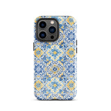 The Blue Mirage for iPhone by Statement Cases features a dual-layered, impact-resistant polycarbonate exterior with a TPU inner liner. Inspired by traditional Portuguese tiles, the blue and yellow patterned case boasts an intricate design of floral and geometric motifs. With its elegant and colorful appearance, the phone's camera is visible at the top left of the case.