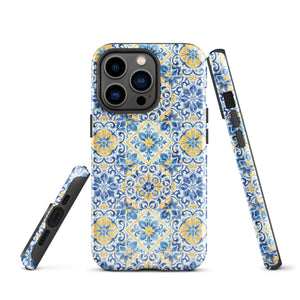 The Blue Mirage for iPhone by Statement Cases features a dual-layered, impact-resistant polycarbonate exterior with a TPU inner liner. Inspired by traditional Portuguese tiles, the blue and yellow patterned case boasts an intricate design of floral and geometric motifs. With its elegant and colorful appearance, the phone's camera is visible at the top left of the case.