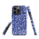 An iPhone encased in the "Mariposa Azul" by Statement Cases, featuring a blue design with an abstract white leaf pattern. The case combines curved and pointed shapes and provides dual-layer protection with TPU lining and impact-resistant polycarbonate. Camera lenses and other top elements remain unobstructed, and "Statement Cases" is inscribed at the bottom.