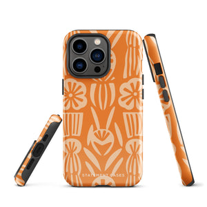 A Savannah Ardiente for iPhone from Statement Cases, featuring a dual-layered phone case in orange with a floral pattern showcasing cream-colored flowers, leaves, and geometric shapes. This impact-resistant polycarbonate case displays "STATEMENT CASES" at the bottom and reveals the camera lenses at the top left corner.