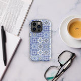 The Lisboa Azul for iPhone by Statement Cases is a smartphone adorned with a dual-layer protection phone case, featuring an intricate blue and white tile pattern. The design showcases various geometric and floral motifs, forming a visually appealing mosaic effect. The impact-resistant camera lenses and flash are prominently visible at the top left.