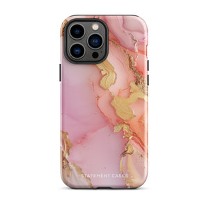 The Gold Blush Marble for iPhone showcases a glossy, marble-patterned case in shades of pink and gold. The decorative design features swirling patterns, seamlessly blending the colors. Crafted with impact-resistant polycarbonate for superior phone protection, "Statement Cases" is written in white at the bottom.