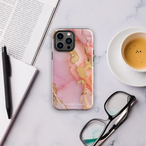 The Gold Blush Marble for iPhone showcases a glossy, marble-patterned case in shades of pink and gold. The decorative design features swirling patterns, seamlessly blending the colors. Crafted with impact-resistant polycarbonate for superior phone protection, "Statement Cases" is written in white at the bottom.