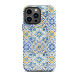 The Blue Mirage for iPhone by Statement Cases features a dual-layered, impact-resistant polycarbonate exterior with a TPU inner liner. Inspired by traditional Portuguese tiles, the blue and yellow patterned case boasts an intricate design of floral and geometric motifs. With its elegant and colorful appearance, the phone's camera is visible at the top left of the case.