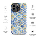 The Blue Mirage for iPhone by Statement Cases features a dual-layered, impact-resistant polycarbonate exterior with a TPU inner liner. Inspired by traditional Portuguese tiles, the blue and yellow patterned case boasts an intricate design of floral and geometric motifs. With its elegant and colorful appearance, the phone's camera is visible at the top left of the case.