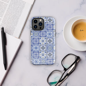 The Lisboa Azul for iPhone by Statement Cases is a smartphone adorned with a dual-layer protection phone case, featuring an intricate blue and white tile pattern. The design showcases various geometric and floral motifs, forming a visually appealing mosaic effect. The impact-resistant camera lenses and flash are prominently visible at the top left.