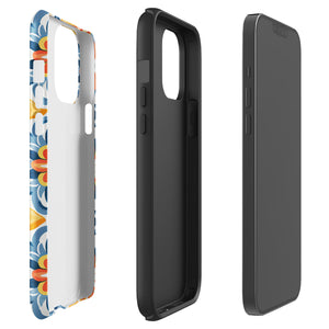 Statement Cases' Mediterranean Bloom for iPhone is showcased, featuring an intricate, colorful pattern. The design includes blue, yellow, and orange floral shapes in a symmetrical arrangement on a light blue background. This durable phone case provides dual-layer protection and is constructed from impact-resistant polycarbonate to safeguard your device.