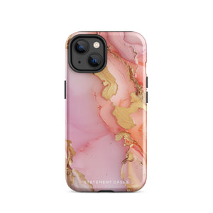 The Gold Blush Marble for iPhone showcases a glossy, marble-patterned case in shades of pink and gold. The decorative design features swirling patterns, seamlessly blending the colors. Crafted with impact-resistant polycarbonate for superior phone protection, "Statement Cases" is written in white at the bottom.