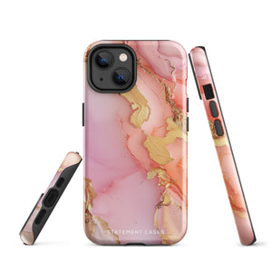 The Gold Blush Marble for iPhone showcases a glossy, marble-patterned case in shades of pink and gold. The decorative design features swirling patterns, seamlessly blending the colors. Crafted with impact-resistant polycarbonate for superior phone protection, "Statement Cases" is written in white at the bottom.