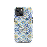 The Blue Mirage for iPhone by Statement Cases features a dual-layered, impact-resistant polycarbonate exterior with a TPU inner liner. Inspired by traditional Portuguese tiles, the blue and yellow patterned case boasts an intricate design of floral and geometric motifs. With its elegant and colorful appearance, the phone's camera is visible at the top left of the case.