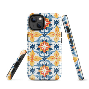 Statement Cases' Mediterranean Bloom for iPhone is showcased, featuring an intricate, colorful pattern. The design includes blue, yellow, and orange floral shapes in a symmetrical arrangement on a light blue background. This durable phone case provides dual-layer protection and is constructed from impact-resistant polycarbonate to safeguard your device.