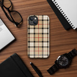 A Neutral Heritage Tartan for iPhone by Statement Cases with a plaid-patterned, impact-resistant polycarbonate case featuring beige, black, white, and red stripes. The durable phone case has the text "STATEMENT CASES" written at the bottom. The phone boasts a triple camera setup with an additional sensor and flash.