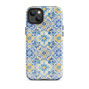 The Blue Mirage for iPhone by Statement Cases features a dual-layered, impact-resistant polycarbonate exterior with a TPU inner liner. Inspired by traditional Portuguese tiles, the blue and yellow patterned case boasts an intricate design of floral and geometric motifs. With its elegant and colorful appearance, the phone's camera is visible at the top left of the case.