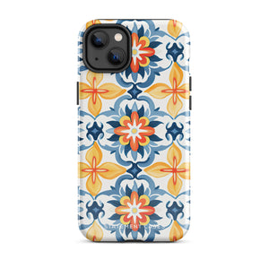 Statement Cases' Mediterranean Bloom for iPhone is showcased, featuring an intricate, colorful pattern. The design includes blue, yellow, and orange floral shapes in a symmetrical arrangement on a light blue background. This durable phone case provides dual-layer protection and is constructed from impact-resistant polycarbonate to safeguard your device.