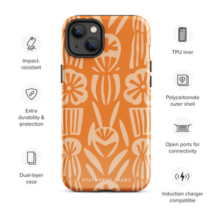 A Savannah Ardiente for iPhone from Statement Cases, featuring a dual-layered phone case in orange with a floral pattern showcasing cream-colored flowers, leaves, and geometric shapes. This impact-resistant polycarbonate case displays "STATEMENT CASES" at the bottom and reveals the camera lenses at the top left corner.