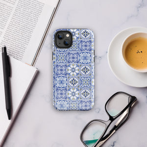 The Lisboa Azul for iPhone by Statement Cases is a smartphone adorned with a dual-layer protection phone case, featuring an intricate blue and white tile pattern. The design showcases various geometric and floral motifs, forming a visually appealing mosaic effect. The impact-resistant camera lenses and flash are prominently visible at the top left.