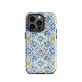 The Blue Mirage for iPhone by Statement Cases features a dual-layered, impact-resistant polycarbonate exterior with a TPU inner liner. Inspired by traditional Portuguese tiles, the blue and yellow patterned case boasts an intricate design of floral and geometric motifs. With its elegant and colorful appearance, the phone's camera is visible at the top left of the case.