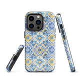 The Blue Mirage for iPhone by Statement Cases features a dual-layered, impact-resistant polycarbonate exterior with a TPU inner liner. Inspired by traditional Portuguese tiles, the blue and yellow patterned case boasts an intricate design of floral and geometric motifs. With its elegant and colorful appearance, the phone's camera is visible at the top left of the case.