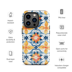 Statement Cases' Mediterranean Bloom for iPhone is showcased, featuring an intricate, colorful pattern. The design includes blue, yellow, and orange floral shapes in a symmetrical arrangement on a light blue background. This durable phone case provides dual-layer protection and is constructed from impact-resistant polycarbonate to safeguard your device.