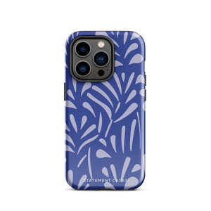 An iPhone encased in the "Mariposa Azul" by Statement Cases, featuring a blue design with an abstract white leaf pattern. The case combines curved and pointed shapes and provides dual-layer protection with TPU lining and impact-resistant polycarbonate. Camera lenses and other top elements remain unobstructed, and "Statement Cases" is inscribed at the bottom.