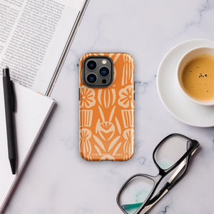 A Savannah Ardiente for iPhone from Statement Cases, featuring a dual-layered phone case in orange with a floral pattern showcasing cream-colored flowers, leaves, and geometric shapes. This impact-resistant polycarbonate case displays "STATEMENT CASES" at the bottom and reveals the camera lenses at the top left corner.