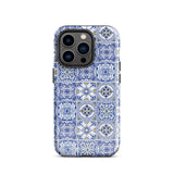 The Lisboa Azul for iPhone by Statement Cases is a smartphone adorned with a dual-layer protection phone case, featuring an intricate blue and white tile pattern. The design showcases various geometric and floral motifs, forming a visually appealing mosaic effect. The impact-resistant camera lenses and flash are prominently visible at the top left.