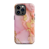 The Gold Blush Marble for iPhone showcases a glossy, marble-patterned case in shades of pink and gold. The decorative design features swirling patterns, seamlessly blending the colors. Crafted with impact-resistant polycarbonate for superior phone protection, "Statement Cases" is written in white at the bottom.