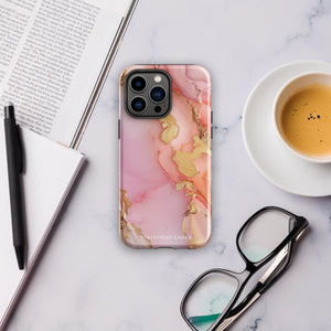 The Gold Blush Marble for iPhone showcases a glossy, marble-patterned case in shades of pink and gold. The decorative design features swirling patterns, seamlessly blending the colors. Crafted with impact-resistant polycarbonate for superior phone protection, "Statement Cases" is written in white at the bottom.