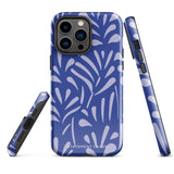 An iPhone encased in the "Mariposa Azul" by Statement Cases, featuring a blue design with an abstract white leaf pattern. The case combines curved and pointed shapes and provides dual-layer protection with TPU lining and impact-resistant polycarbonate. Camera lenses and other top elements remain unobstructed, and "Statement Cases" is inscribed at the bottom.