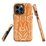 A Savannah Ardiente for iPhone from Statement Cases, featuring a dual-layered phone case in orange with a floral pattern showcasing cream-colored flowers, leaves, and geometric shapes. This impact-resistant polycarbonate case displays "STATEMENT CASES" at the bottom and reveals the camera lenses at the top left corner.