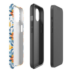 Statement Cases' Mediterranean Bloom for iPhone is showcased, featuring an intricate, colorful pattern. The design includes blue, yellow, and orange floral shapes in a symmetrical arrangement on a light blue background. This durable phone case provides dual-layer protection and is constructed from impact-resistant polycarbonate to safeguard your device.