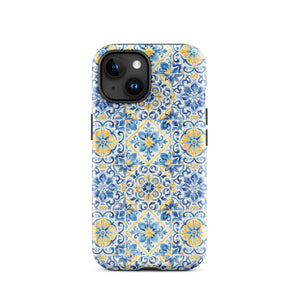 The Blue Mirage for iPhone by Statement Cases features a dual-layered, impact-resistant polycarbonate exterior with a TPU inner liner. Inspired by traditional Portuguese tiles, the blue and yellow patterned case boasts an intricate design of floral and geometric motifs. With its elegant and colorful appearance, the phone's camera is visible at the top left of the case.