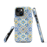 The Blue Mirage for iPhone by Statement Cases features a dual-layered, impact-resistant polycarbonate exterior with a TPU inner liner. Inspired by traditional Portuguese tiles, the blue and yellow patterned case boasts an intricate design of floral and geometric motifs. With its elegant and colorful appearance, the phone's camera is visible at the top left of the case.