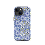 The Lisboa Azul for iPhone by Statement Cases is a smartphone adorned with a dual-layer protection phone case, featuring an intricate blue and white tile pattern. The design showcases various geometric and floral motifs, forming a visually appealing mosaic effect. The impact-resistant camera lenses and flash are prominently visible at the top left.