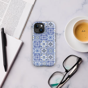 The Lisboa Azul for iPhone by Statement Cases is a smartphone adorned with a dual-layer protection phone case, featuring an intricate blue and white tile pattern. The design showcases various geometric and floral motifs, forming a visually appealing mosaic effect. The impact-resistant camera lenses and flash are prominently visible at the top left.