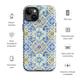 The Blue Mirage for iPhone by Statement Cases features a dual-layered, impact-resistant polycarbonate exterior with a TPU inner liner. Inspired by traditional Portuguese tiles, the blue and yellow patterned case boasts an intricate design of floral and geometric motifs. With its elegant and colorful appearance, the phone's camera is visible at the top left of the case.