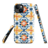 Statement Cases' Mediterranean Bloom for iPhone is showcased, featuring an intricate, colorful pattern. The design includes blue, yellow, and orange floral shapes in a symmetrical arrangement on a light blue background. This durable phone case provides dual-layer protection and is constructed from impact-resistant polycarbonate to safeguard your device.