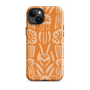 A Savannah Ardiente for iPhone from Statement Cases, featuring a dual-layered phone case in orange with a floral pattern showcasing cream-colored flowers, leaves, and geometric shapes. This impact-resistant polycarbonate case displays "STATEMENT CASES" at the bottom and reveals the camera lenses at the top left corner.