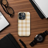 A Gingham Grace for iPhone by Statement Cases is covered with a protective case featuring a beige and white checkered pattern. The case's design includes a matte finish, dual-layer protection with an impact-resistant polycarbonate exterior and TPU lining, and the text "Statement Cases" printed near the bottom. The phone's cameras and buttons are visible.