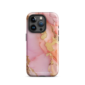 The Gold Blush Marble for iPhone showcases a glossy, marble-patterned case in shades of pink and gold. The decorative design features swirling patterns, seamlessly blending the colors. Crafted with impact-resistant polycarbonate for superior phone protection, "Statement Cases" is written in white at the bottom.