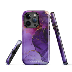 A Statement Cases Golden Orchid Marble for iPhone with a case featuring an abstract design of swirling purple, pink, and gold hues over a white background. The marbled patterns with metallic accents provide dual-layer protection and are impact-resistant. The top of the case has cutouts for the phone's camera lenses and is induction charging compatible.