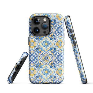 The Blue Mirage for iPhone by Statement Cases features a dual-layered, impact-resistant polycarbonate exterior with a TPU inner liner. Inspired by traditional Portuguese tiles, the blue and yellow patterned case boasts an intricate design of floral and geometric motifs. With its elegant and colorful appearance, the phone's camera is visible at the top left of the case.