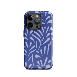 An iPhone encased in the "Mariposa Azul" by Statement Cases, featuring a blue design with an abstract white leaf pattern. The case combines curved and pointed shapes and provides dual-layer protection with TPU lining and impact-resistant polycarbonate. Camera lenses and other top elements remain unobstructed, and "Statement Cases" is inscribed at the bottom.