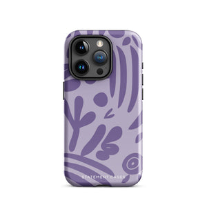 The Luna Morada for iPhone by Statement Cases is a durable phone case with a purple protective exterior featuring abstract dark purple and lavender patterns. The design includes geometric shapes and curves, giving it a modern artistic look. Made from impact-resistant polycarbonate, the lower part of the case prominently displays "STATEMENT CASES.