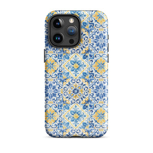 The Blue Mirage for iPhone by Statement Cases features a dual-layered, impact-resistant polycarbonate exterior with a TPU inner liner. Inspired by traditional Portuguese tiles, the blue and yellow patterned case boasts an intricate design of floral and geometric motifs. With its elegant and colorful appearance, the phone's camera is visible at the top left of the case.