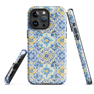 The Blue Mirage for iPhone by Statement Cases features a dual-layered, impact-resistant polycarbonate exterior with a TPU inner liner. Inspired by traditional Portuguese tiles, the blue and yellow patterned case boasts an intricate design of floral and geometric motifs. With its elegant and colorful appearance, the phone's camera is visible at the top left of the case.